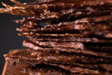 Ahşap bir tahtanın üzerinde, baharatlı bir et parçasının yakın çekimi. Restoran menüsü, bir dizi farklı yemeğin fotoğrafları.