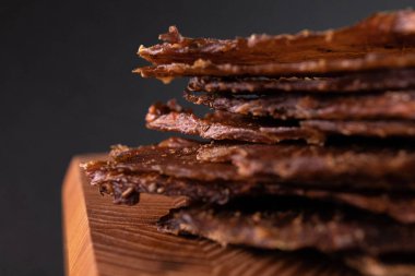 Ahşap bir tahtanın üzerinde, baharatlı bir et parçasının yakın çekimi. Restoran menüsü, bir dizi farklı yemeğin fotoğrafları.