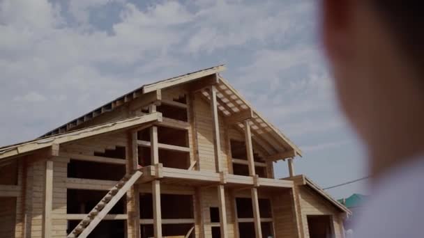 Construtor olhando para construir uma casa de madeira. o rosto não é visível — Vídeo de Stock