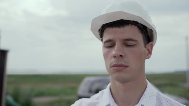 Ingenieur Bouwvoorman in helm kijkt naar een bouwplaats. gezichtsclose-up — Stockvideo