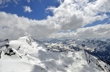 Avusturya Avrupa dağlarının tepelerinde karlar, bulutlar ve mavi gökyüzü