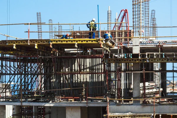 Trabalhadores que trabalham entre andaimes e concreto em construção — Fotografia de Stock