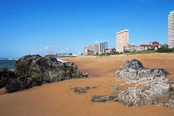 Lege rotsachtige strand tegen Skyline van de stad en de blauwe hemel — Stockfoto