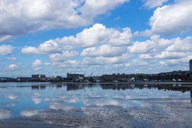 Liman düşük Tide bulutlu mavi gökyüzü yansımaları ile
