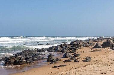 Okyanus dalgaları ve mavi gökyüzü Beach iskelesinden kayalar