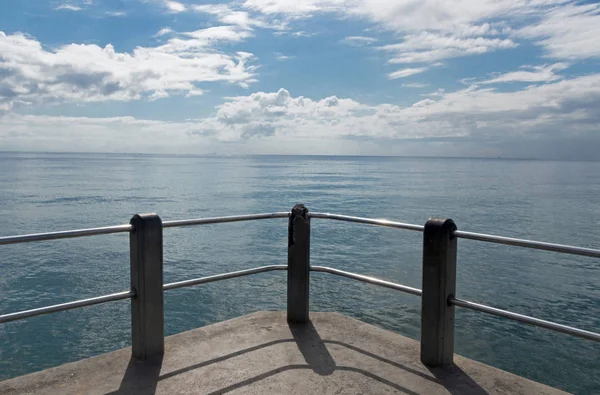 Betongeländer gegen Meer und blauen bewölkten Himmel — Stockfoto