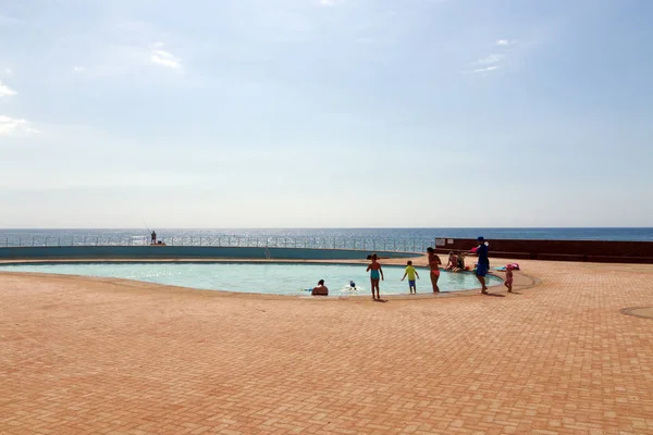 Gente nadando en la piscina frente al océano Skyline — Foto de Stock