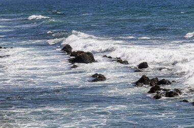 Dalgalar ve mavi okyanus kayaların üzerinden yıkama