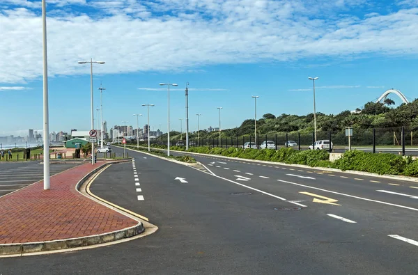 Asfaltovou silnici a zelené vegetace proti panorama města — Stock fotografie