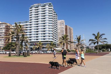  Döşeli kıyısındaki Beachfront üzerinde yürüyen insanlar