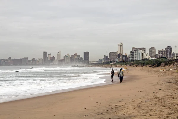 Okänd fiskare på stranden mot mulet Durban stadssilhuetten — Stockfoto