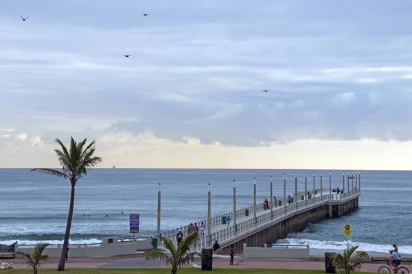 Visitantes da manhã cedo em frente à praia e cais contra Skyline — Fotografia de Stock