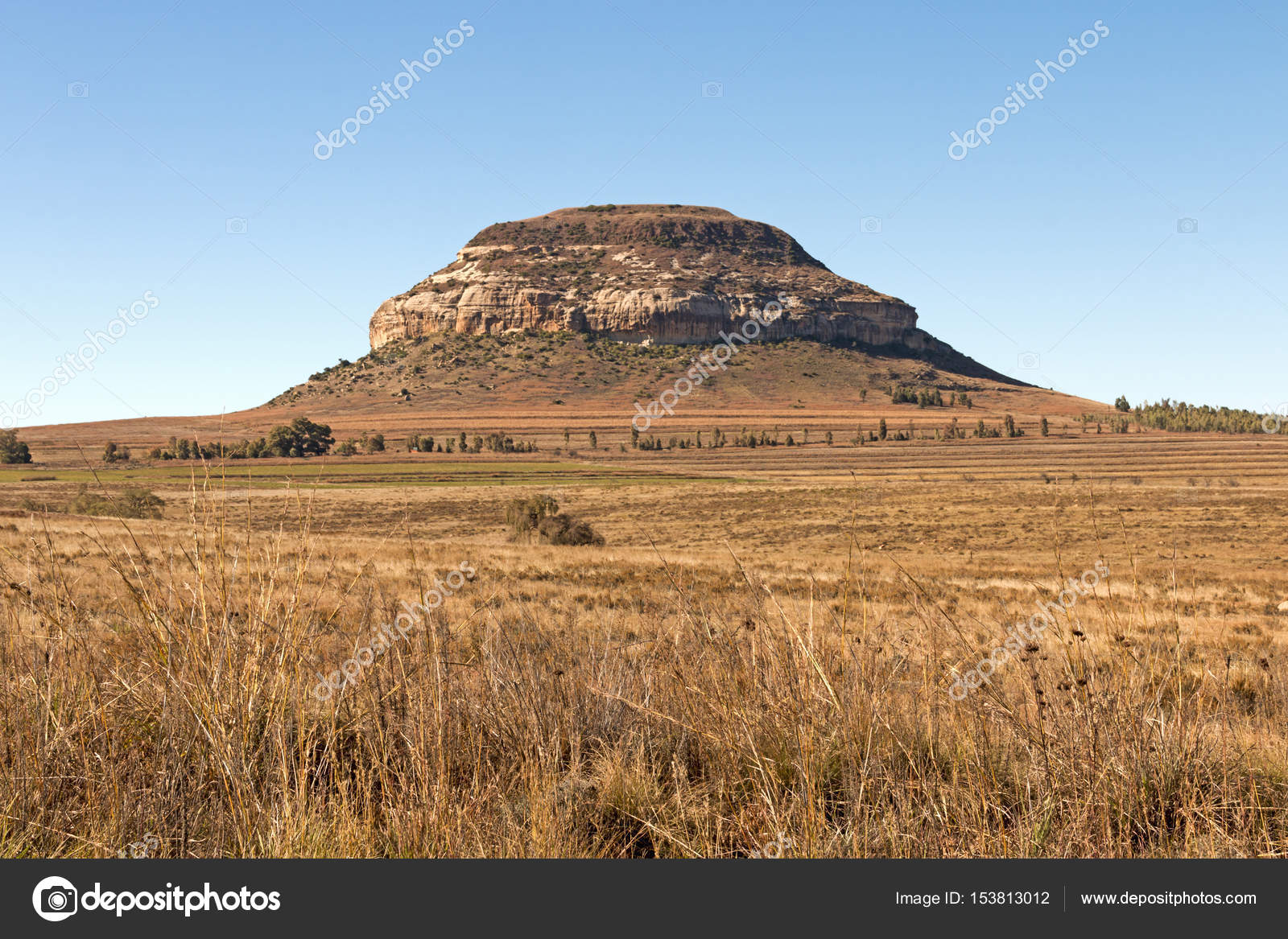 Césped contra las montañas rocosas y el cielo azul de color naranja