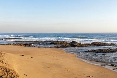Kayalık okyanus kıyı ve mavi gökyüzü manzara karşı plaj