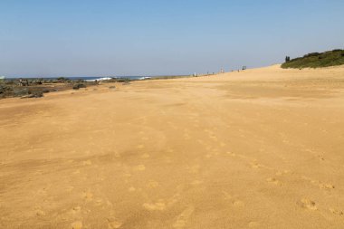 Sandy Beach ve mavi gökyüzü karşı kayalık sahil