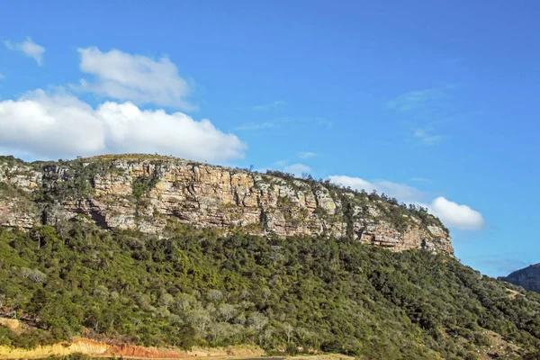 Grüne Bäume und Felswände gegen blauen bewölkten Himmel — Stockfoto