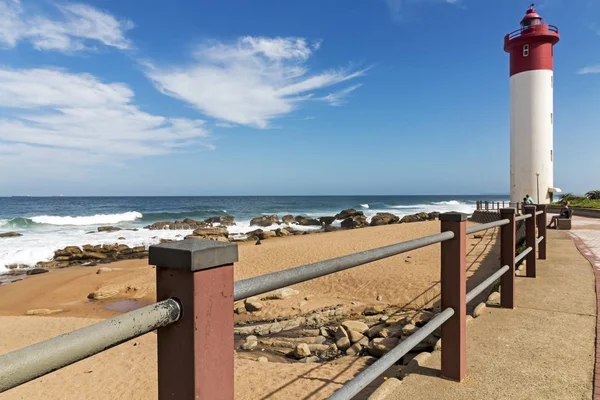 Barrera contra el faro rojo y blanco y el paisaje marino azul — Foto de Stock