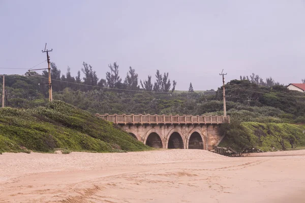 Pont arqué avec ligne de chemin de fer longeant la plage — Photo