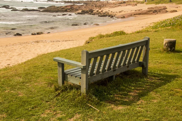 Panca di legno verde su erba in spiaggia — Foto Stock