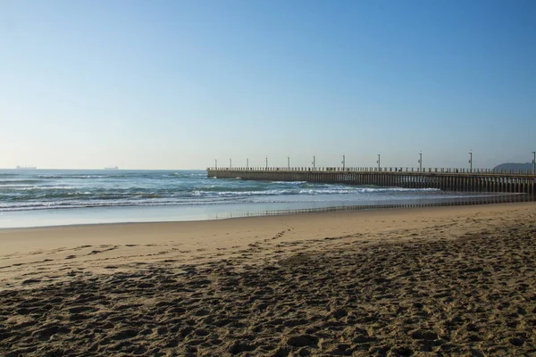 Pegadas Areia Praia Úmida Com Cais Concreto Fundo — Fotografia de Stock