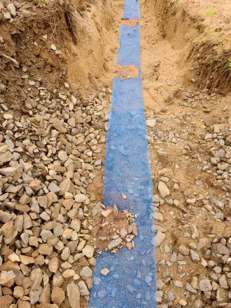 Schützengraben mit blauem Plastikschutzband. Markierung von Kabeln unter Lehm beim Bau des Internets — Stockfoto