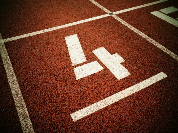 Número cuatro. Número de pista blanca en pista de carreras de goma roja , —  Fotos de Stock