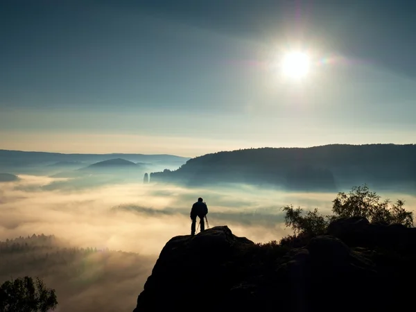 Fotógrafo com tripé e câmera no penhasco e pensando. Paisagem nebulosa sonhadora — Fotografia de Stock