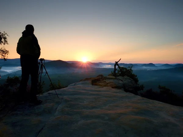 Silhouette of landscape photographer on peak above misty valley. — Stock Photo, Image