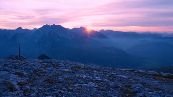 Timelapse of sunset over mountain peaks. Sun goes down over sharp peaks of Alps. Pink purple sky. Colorful flare in camera lens. — Stock Video
