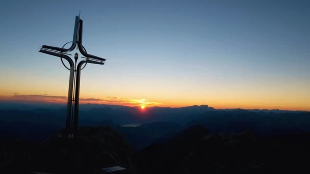 Hora do amanhecer dos Alpes. Cruz de ferro no topo da montanha em Alp. Cruze no topo de um pico de montanhas como típico nos Alpes. Monumento aos alpinistas mortos — Vídeo de Stock