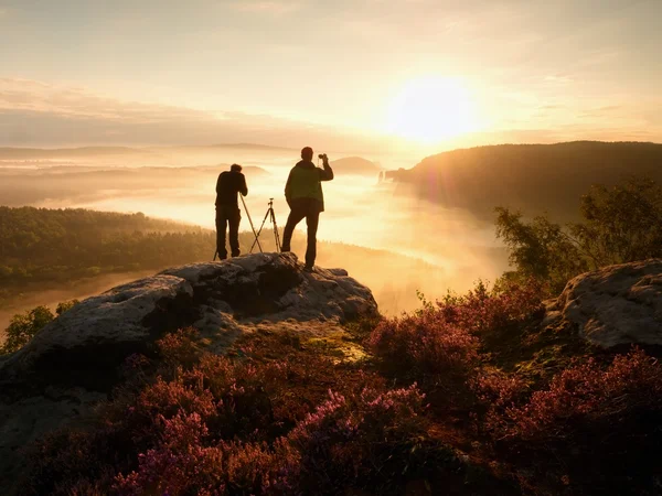 Fotoğrafçılar cliff üzerinde kalmak ve fotoğraf çeker. Rüya gibi adamlara manzara, turuncu sis — Stok fotoğraf