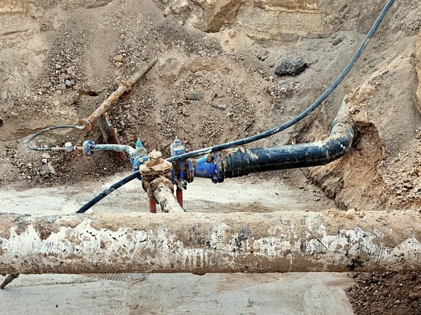 Fosa de excavación. Antiguo tubo de agua de bebida de 500 mm con brazo de 150 mm con válvulas de compuerta, accesorios de unión corroídos. Tubos antes de reparar las tuberías. Aislamiento del asfalto . — Foto de Stock