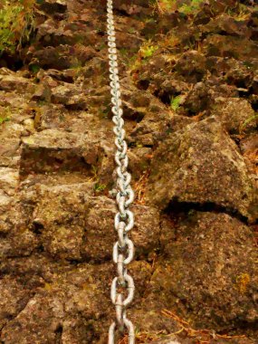 Suluboya etkisi. Kumtaşı kaya zincir ve çelik cıvata çapa göz detay. Çelik zincirin son düğümü. Ferrata ile dağcılar yolu. Demir zincir blokta sabit.