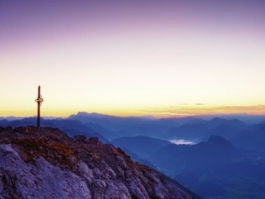 Dağ tepe Alpleri'nde çelik haç. Keskin kayalık Zirvesi, şafak Güneş gökyüzünde. 