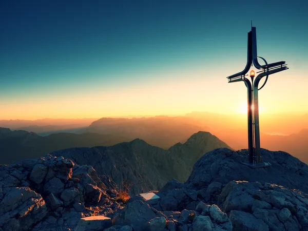 Cross raised  at Alpine mountain peakSharp rocks, Sun in sky. — Stock Photo, Image