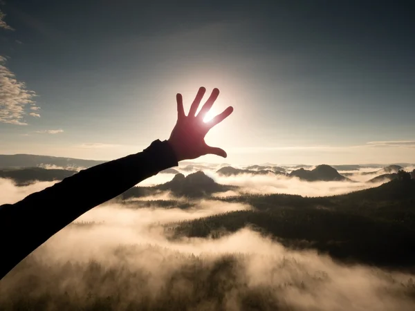 Man hand touch Sun. Misty daybreak in a beautiful hills. Hilly landscape in fog — Stock Photo, Image