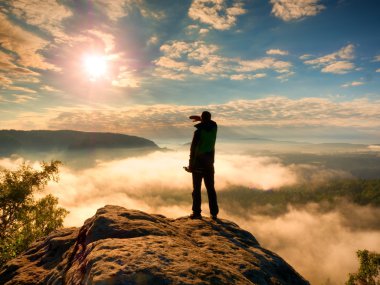 Tripod üzerinde cliff ve düşünme ile profesyonel fotoğrafçı. Rüya gibi sis