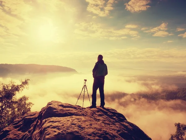 Professional photographer with tripod and camera thinking. Creamy heavy fog i