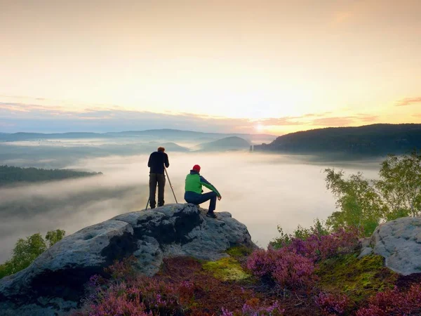 Hiker and photo enthusiast stay with tripod on cliff and takes photos. — Stock Photo, Image