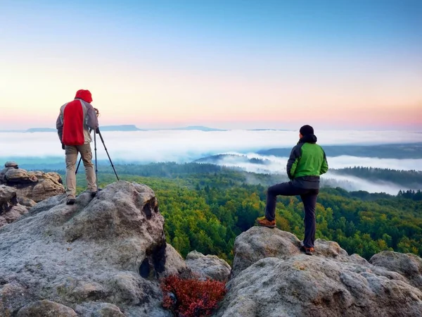 Escursionista e fotografo rimangono con treppiede sulla scogliera e scattano foto. Autunno paesaggio ventoso , — Foto Stock