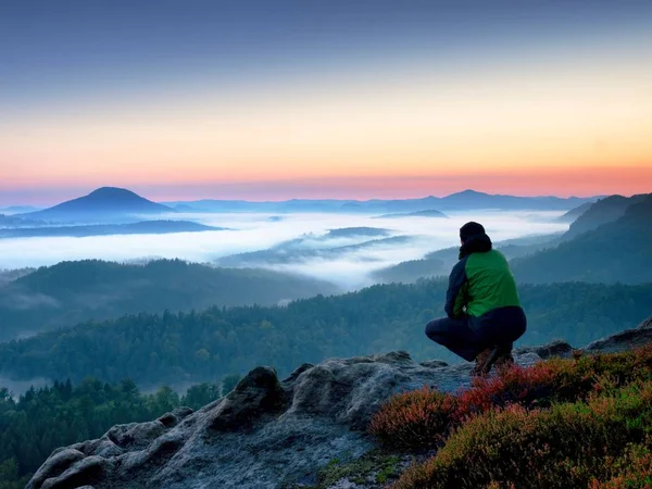 Randonneur homme sur le rocher veille sur la brume crémeuse et le paysage matin brumeux . — Photo