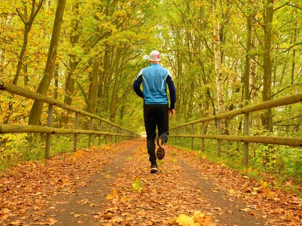 Sportsman en t-shirt bleu et pantalon noir courir sur la route. L'homme court lentement. — Photo