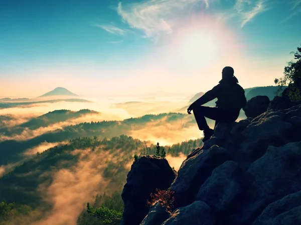 Πεζοπόρος άνθρωπος να ξεκουραστείτε στην κορυφή του βουνού. Ο άνθρωπος βάζει στη σύνοδο κορυφής, παρακάτω φθινόπωρο κοιλάδα. — Φωτογραφία Αρχείου