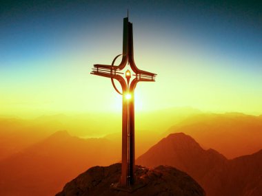 Dağ tepe Alpleri'nde çelik haç. Keskin kayalık Zirvesi, şafak Güneş gökyüzünde. 