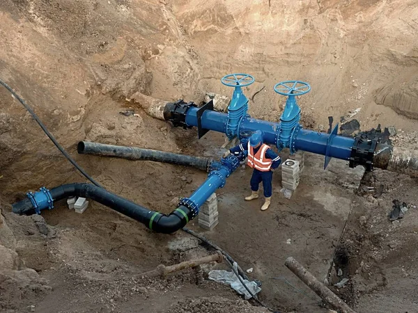 500毫米饮水管闸阀地下技术专家。 在用粘土覆盖之前检查修理过的管道. 沥青隔离 — 图库照片