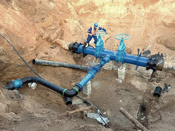 Especialista técnico subterrâneo na válvula de portão em tubos de água de bebida de 500mm. Verificação de tubulação reparada antes de cobrir pelo barro. Isolamento de asfalto — Fotografia de Stock