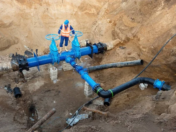 Technical expert underground at gate valve on 500mm drink water pipes. Check of repaired piping before covering by clay. Asphalt isolation — Stock Photo, Image