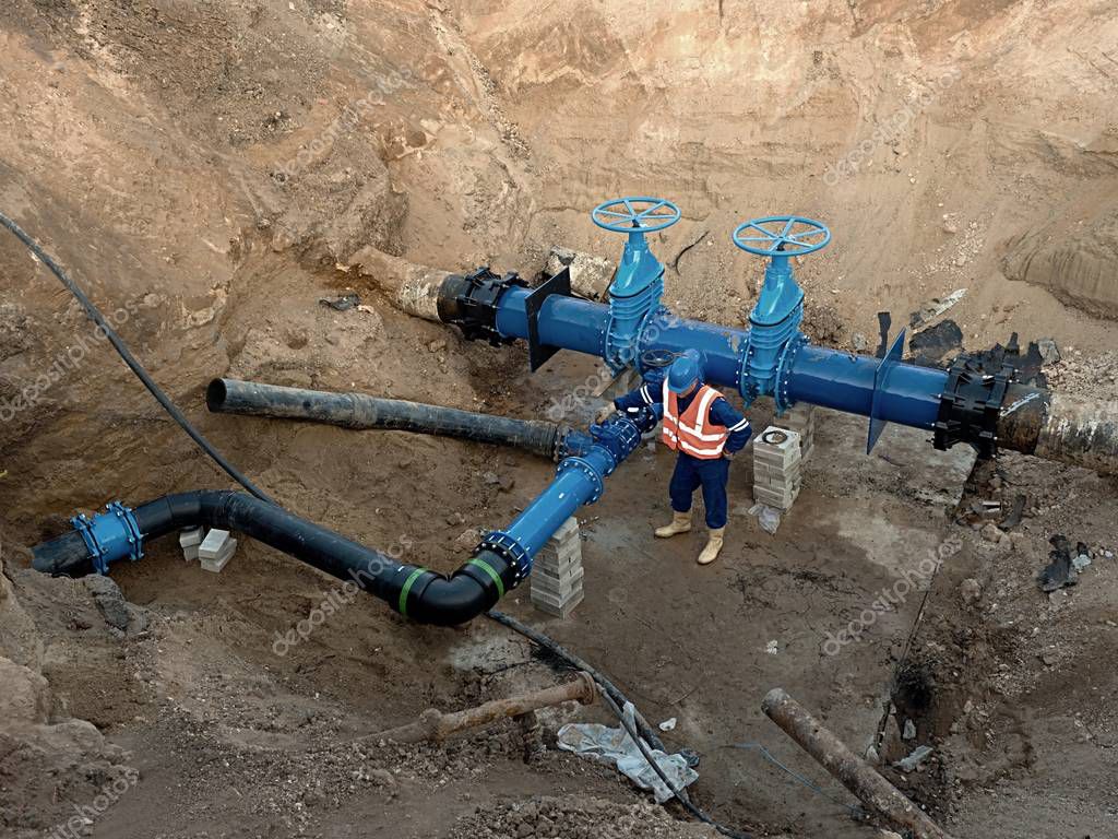 Technical expert underground at gate valve on 500mm drink water pipes.  Check of repaired piping before covering by clay. Asphalt isolation Stock  Photo by ©rdonar 130176522