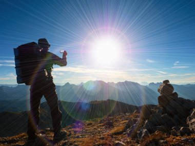 Lens flare kusur. Turist Rehberi Alps tepe üzerinde fotoğrafı çeker. Büyük sırt çantası ile güçlü fiyatı  