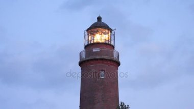 Çam ormanı yukarıda eski deniz feneri gün batımından önce shinning. Güçlü uyarı ışığı ile aydınlatılan kulesi. Kırmızı tuğla, demir parmaklık spot cam kapağı çevresinde Galerisi'yle inşa deniz feneri. 